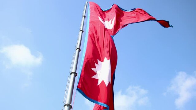 Nepal national flag. Nepal flag waving in the blue sky. Nepal Flag Flying High With Pride.