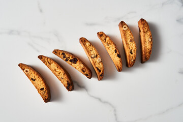 Crisp Almond and Cranberry Biscotti Lined Up on Marble Surface with Soft Shadow Accents