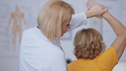 A woman does an exercise for bone health with her doctor, rehabilitating after trauma