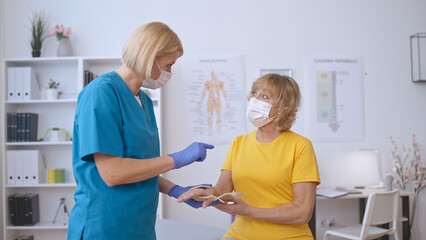Obraz premium A caring nurse offers advice on caring for a senior patient's injured wrist, facilitating trauma treatment