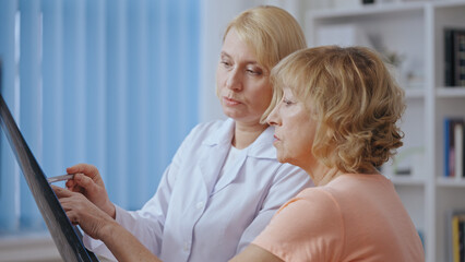 Obraz premium A doctor and her senior patient review an x-ray image during a medical consultation