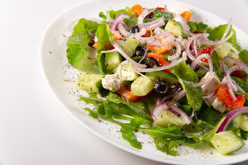 Traditional greek salad with fresh ingredients, feta cheese, olives, red tomatoes, cucumbers and greens
