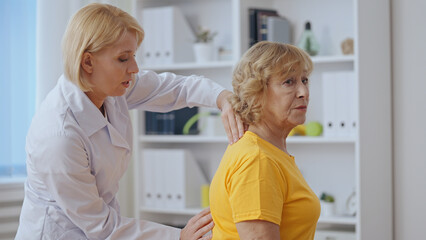 A senior lady feels pain in her back during a doctor's examination, indicating a spinal cord injury