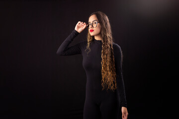 Happy young woman in black clothes on a black background with cinematic lighting
