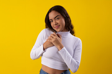 Young, happy woman wearing a white blouse, happy on yellow background