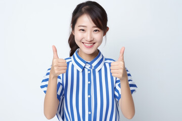 A woman wearing a blue and white shirt enthusiastically raises her thumb in approval.