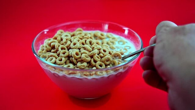 Hand with spoon picking cheerios from milk and returning back in slow motion