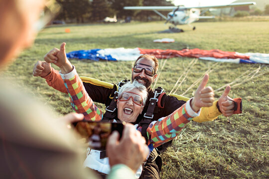 Happy senior woman landing with skydiving instructor