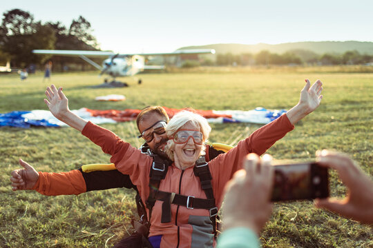 Happy senior woman landing with skydiving instructor
