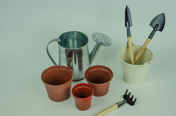 garden objects on a light background, watering can pots for planting, shovels with rakes for...