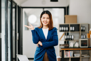 Young attractive Asian female office worker business suits smiling at camera in office .