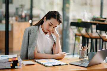 Asian woman feeling migraine head strain.Overworked businesswoman financier while working