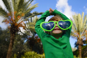 Funny preschooler boy wearing funny heart-shaped glasses. Concept: love of travel, mother's day. Portrait of a child - symbol of love