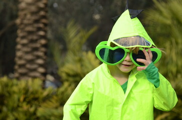 A boy in a raincoat and sunglasses. The vagaries of nature in the tropics, rain and sun, what is...