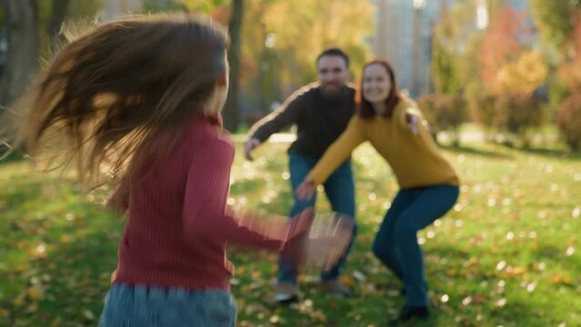 Happy family playing hugging in park sunny autumn mother father waiting little child kid daughter girl run to parents running hugging mommy dad hug cuddle embrace smiling play game love closeness