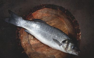 fresh, raw sea bass fish, in a wooden plate, top view, no people.