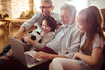 Joyful Grandparents with Grandchildren Watching Soccer Game on Laptop at Home