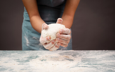 Baker kneading dough for pizza or artisan bread with his hands, prepare ingredients for food, baking pastry
