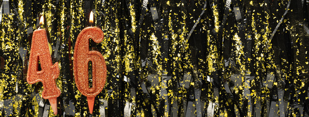 Burning red birthday candles on glitter tinsel background, number 46. Banner.