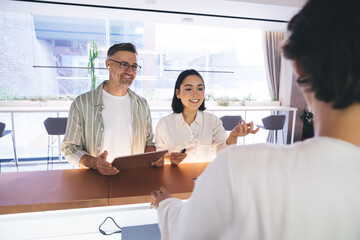 Happy Caucasian man in optical spectacles for vison correction and Asian female colleague smiling...