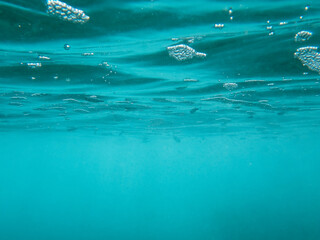 Burbujas de color azul profundo y peces bajo la superficie del agua. Fotografía de la superficie...