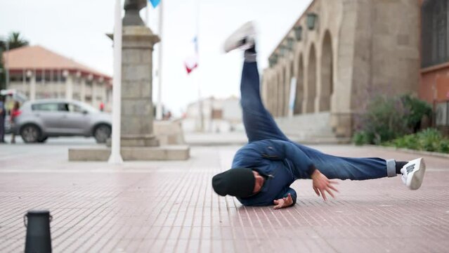 latin American breakdancer guy performing downrock or floor based footwork on the street