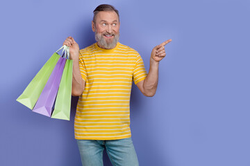 Portrait of pensioner person wear yellow t-shirt hold new clothes look directing at sale empty...