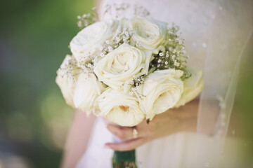 wedding bouquet in bride's hands. beautiful tender wedding bouquet of white roses flowers in hands of the bride. 