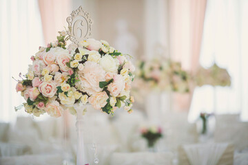 Beautiful flowers on table in wedding day. Table decor with flowers table numbers and candles. Boquet of flowers  on arranged table. 