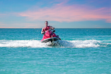 Young guy cruising on the caribbean sea on a jet ski