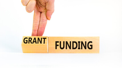 Grant funding symbol. Concept words Grant funding on beautiful wooden blocks. Beautiful white table white background. Businessman hand. Business and grant funding concept. Copy space.