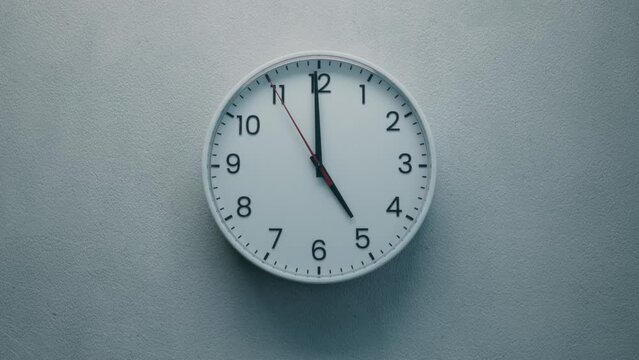 Cinematic Shot of White Office Wall Clock with Red Second Hand that counting down the Seconds to Twelve. Concept: Anticipation, Running out of Time, Deadline, Tension and Passage of time.