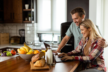 Morning Bliss: Couple Enjoying a Healthy Breakfast and Laptop Time in a Sunlit Kitchen