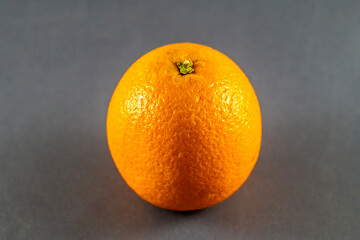 A close up view of a whole orange on a dark marble platter