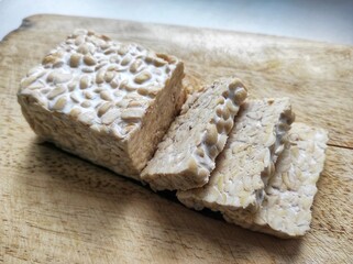 Sliced ​​raw soybean tempeh, a typical Indonesian food on a cutting board.