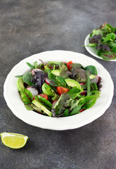 Fresh mix salad with avocado, tomato and radish on a brown background. Avocado salad. 