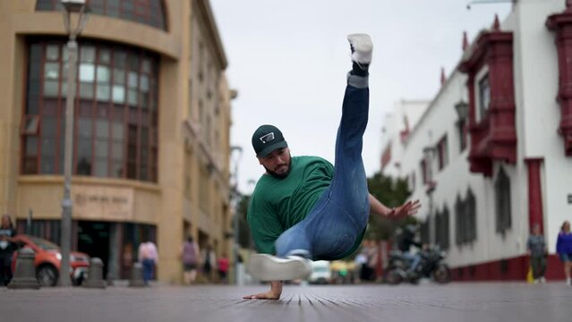 latin American breakdancer guy performing downrock or floor based footwork on the street
