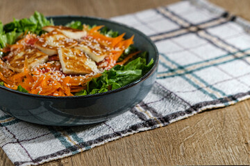 green salad with greek pan fried cheese served on wooden background with kitchen cloth textile napkin
