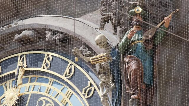 Blue statue of man playing violin near clock in medieval architecture