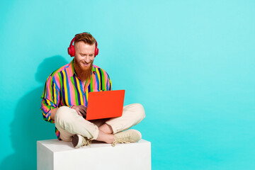Full body length size photo of red hair bearded man professional in headphones coding using netbook...