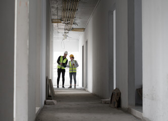 Caucasian engineer man and woman working with tablet computer and paper work in building at construction site	