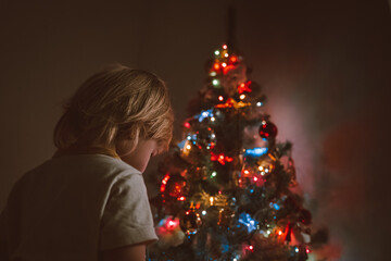 Little child near the Christmas tree with a garland