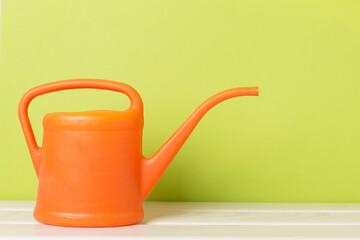 Orange watering can on wooden table