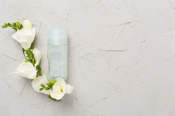 Cosmetic bottle with freesia flowers on concrete background, top view