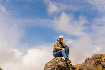 mujer sentada en las rocas de una montaña 