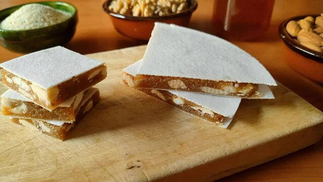 Cut pieces of Alajú on a wooden board, a variety of nougat traditional from the regions of Cuenca and Rincón de Ademuz in Spain, made with almonds and other nuts, honey and breadcrumbs