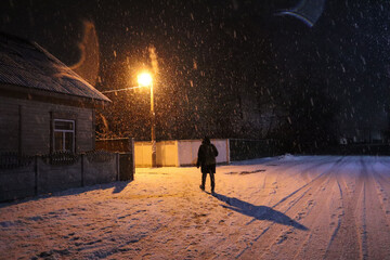 Male silhouette on a snowy street with a burning lantern