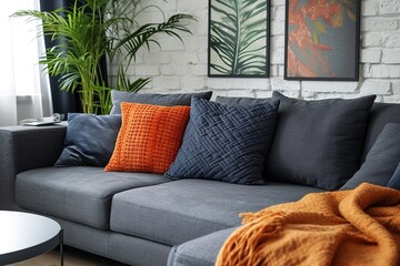 Patterned pillow on grey corner sofa in living room interior with plant and poster. Real photo.