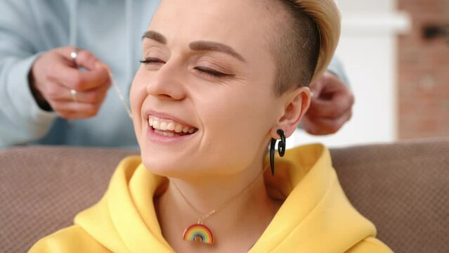 In an intimate moment, one lesbian partner presents a rainbow LGBT pendant as a gift, tenderly placing it around the neck of her smiling girlfriend, reinforcing their bond and shared identity.