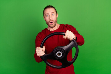 Portrait of astonished guy with bristle wear red sweatshirt hold steering wheel staring at accident isolated on green color background